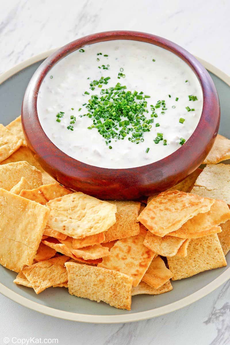 a bowl of clam dip and crackers on a platter.