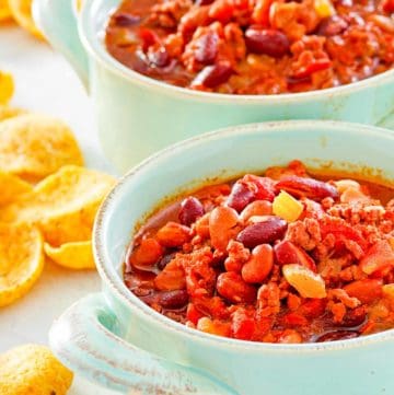 two bowls of crockpot chili and corn chips.