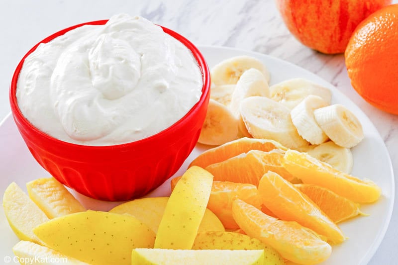 fruit dip in a bowl and sliced fresh fruit on a plate.