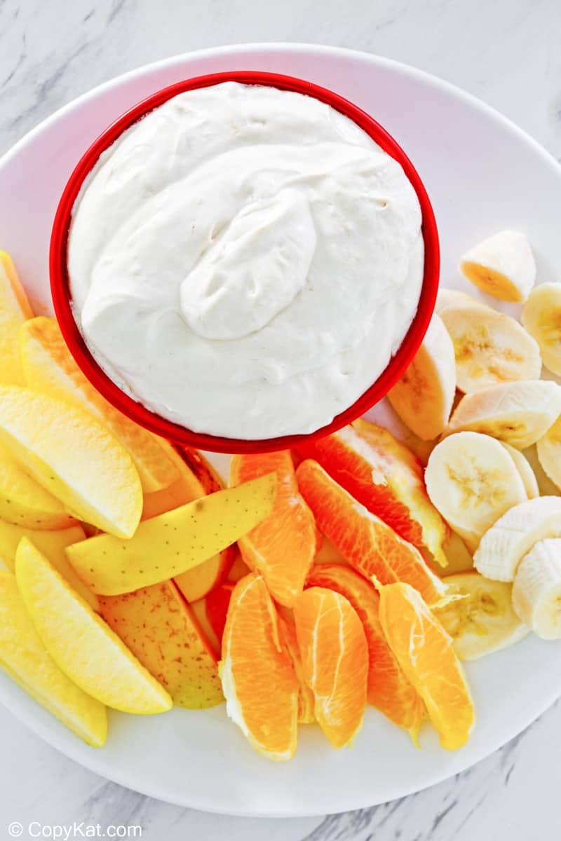 overhead view of a bowl of fruit dip and fresh fruit on a plate.