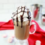 homemade McDonald's peppermint mocha with whipped cream and chocolate syrup and a red kitchen towel.