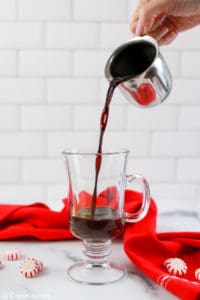 pouring coffee into a mug with peppermint chocolate syrup.
