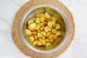 cut potatoes in a bowl tossed with oil, salt, and pepper.