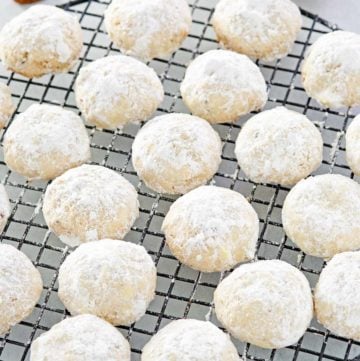 pecan sandies cookies on a round wire rack and a bowl of pecans.