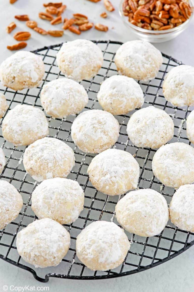 pecan sandies cookies on a round wire rack and a bowl of pecans.