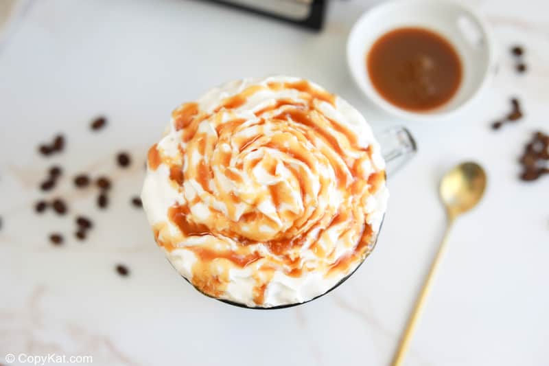 overhead view of a homemade Starbucks caramel latte with whipped cream and caramel drizzle.