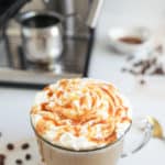 homemade Starbucks caramel latte and an espresso machine behind it.