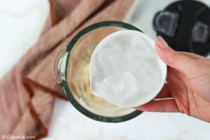 adding ice to a blender to make a vanilla frappuccino.