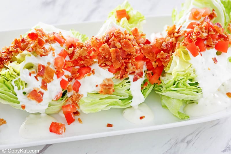 three servings of classic wedge salad on a platter.