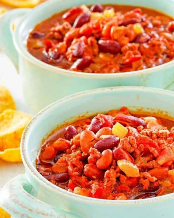 two bowls of crockpot chili and corn chips.