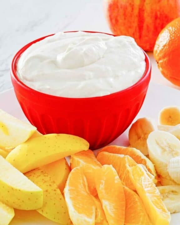 fruit dip in a bowl and various fresh fruit next to it.