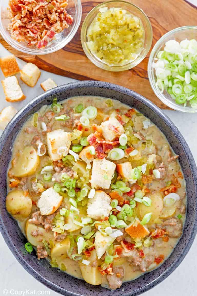 overhead view of cheeseburger soup in a bowl and various toppings for it.