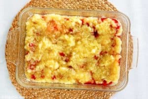 cherry and pineapple layers for a dump cake in a baking dish.