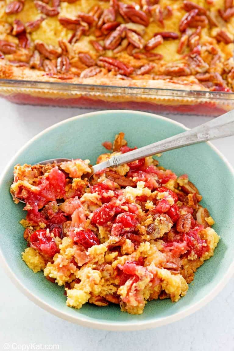 cherry pineapple dump cake in a baking dish and a serving in a bowl.