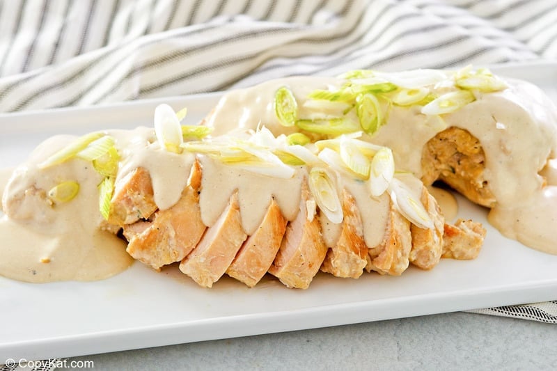 sliced chicken topped with cream cheese sauce on a platter.