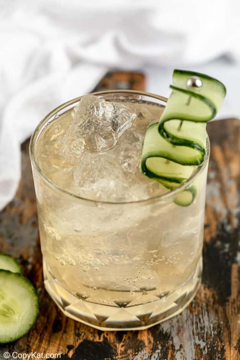 fleur de lis cucumber gin cocktail in a rock glass garnished with cucumber.
