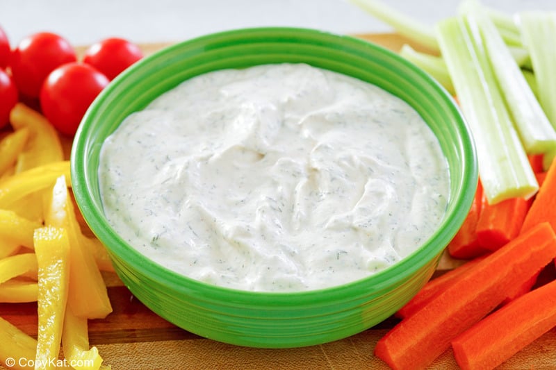 dill dip in a bowl with assorted cut vegetables around it.