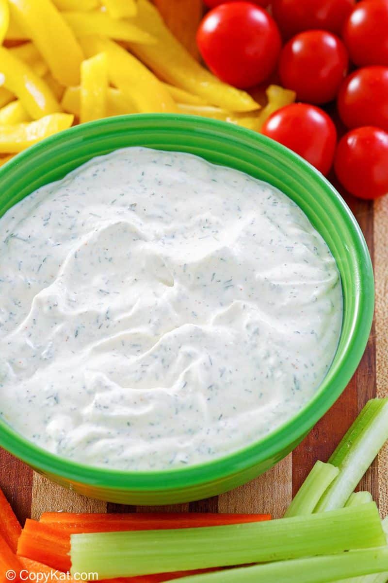 a bowl of dill dip and assorted vegetables.