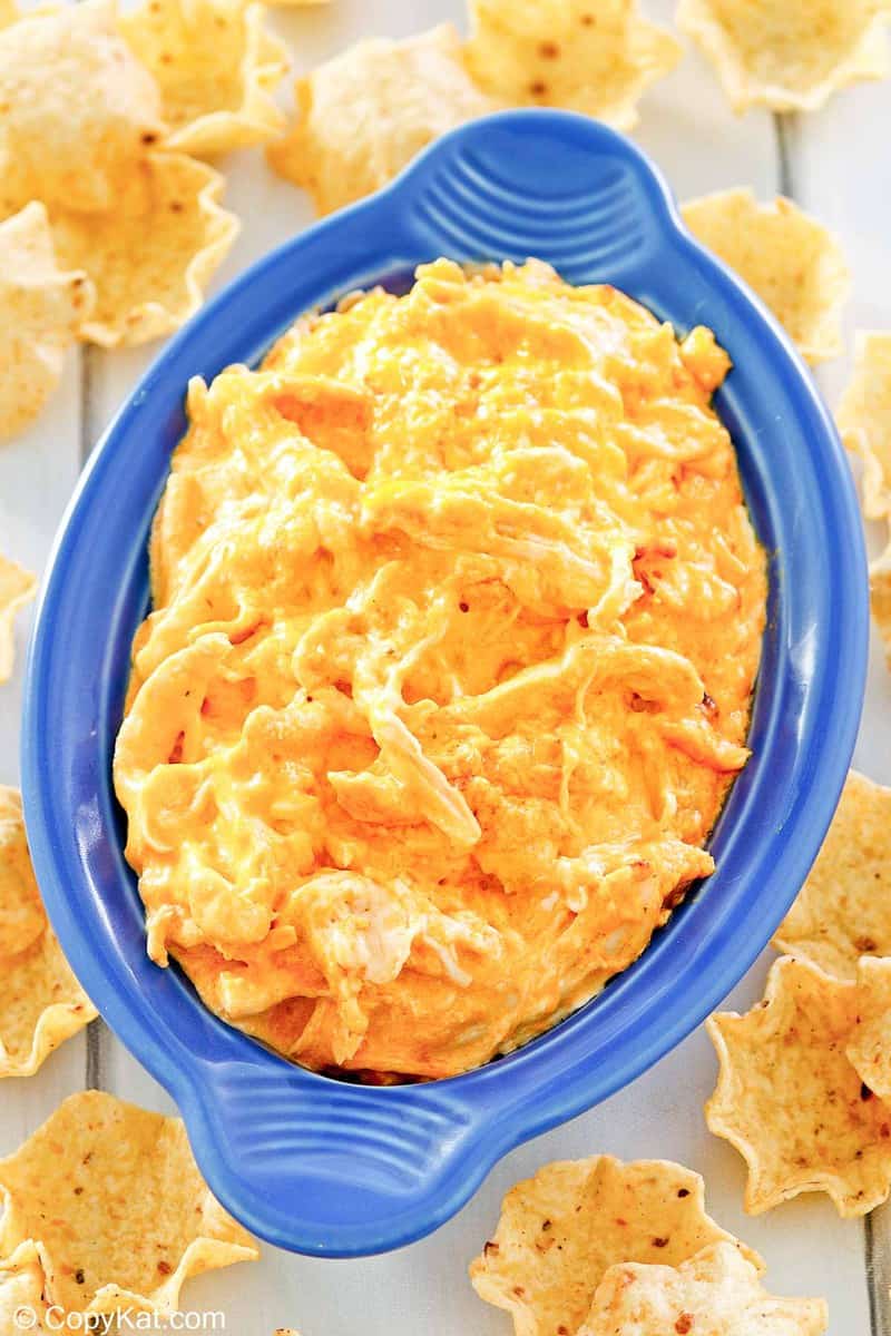 Frank's Buffalo chicken dip in a blue dish and tortilla chips around it.