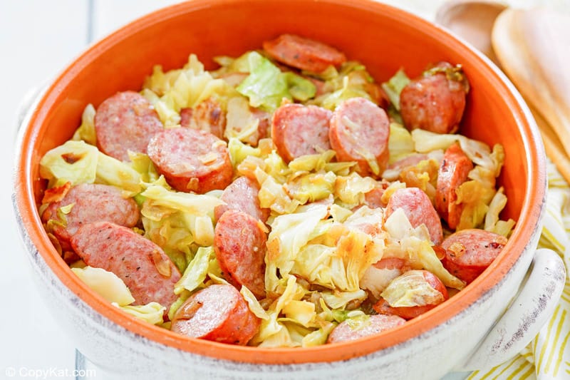 a bowl of fried cabbage with bacon and sausage.