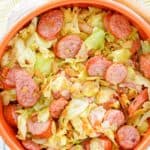 overhead view of fried cabbage and sausage in a bowl.