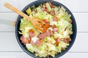 chopped cabbage with bacon and sausage in a skillet.