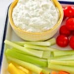 a bowl of green goddess dip and vegetables on a tray.