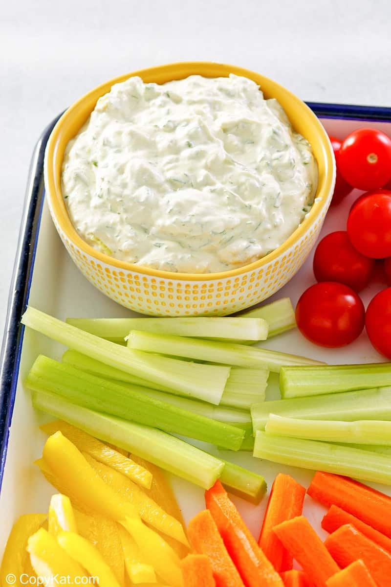 a bowl of green goddess dip and vegetables on a tray.