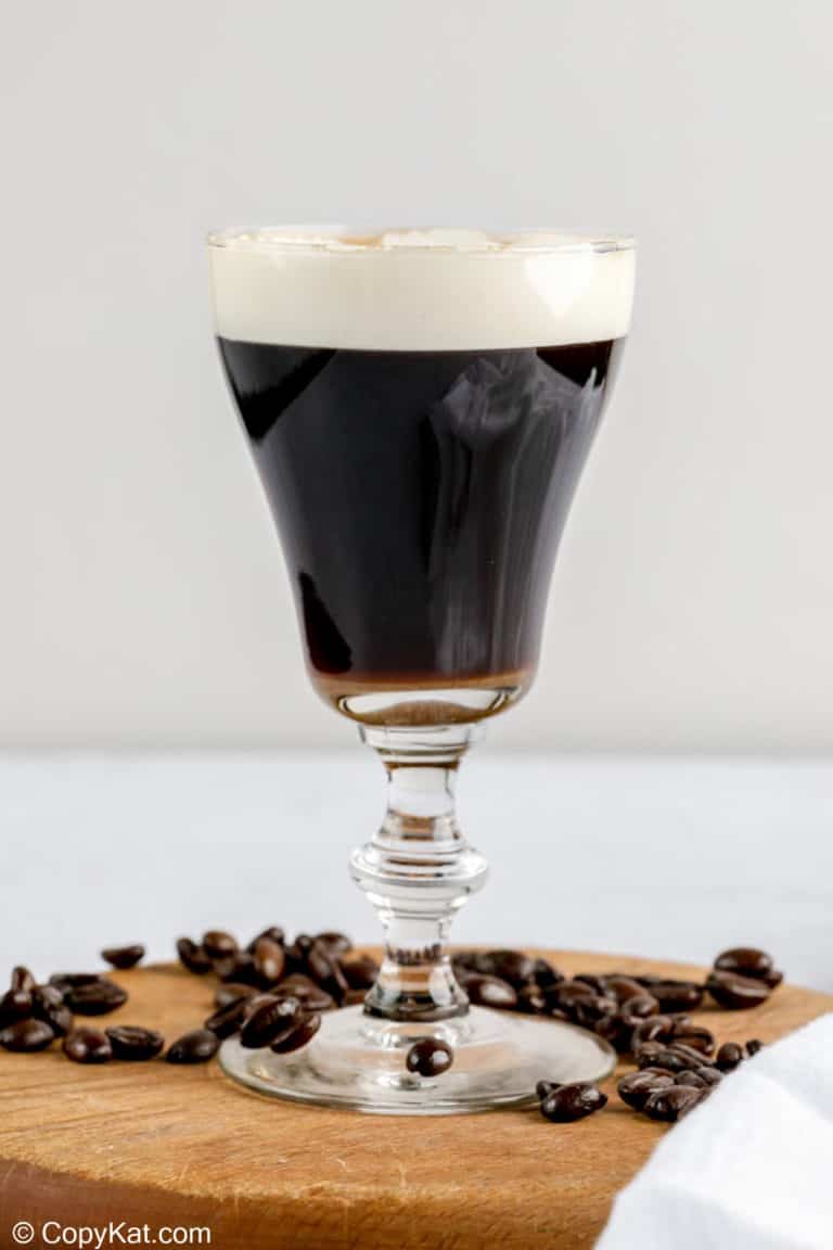 Irish coffee on a wood board with coffee beans around it.