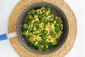 cooking broccoli, kale, and cabbage in a skillet.