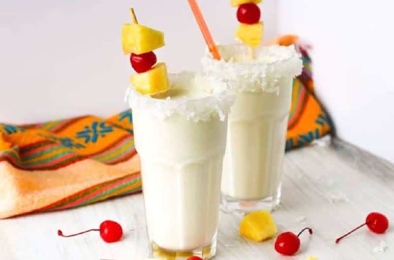 pina colada milkshakes garnished with cherries, pineapple, and coconut.