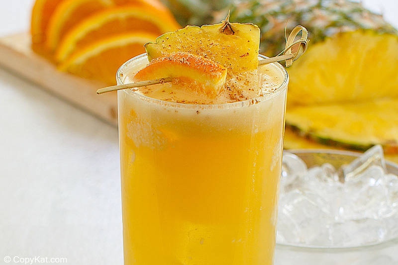 homemade painkiller drink garnished with orange and pineapple.