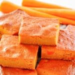 stack of carrot pudding slices and three carrots.