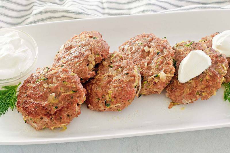 chicken croquettes and sour cream on a white platter.