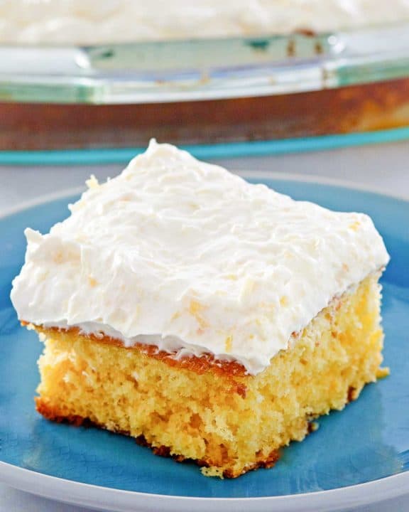 mandarin orange cake slice on a plate in front of the cake.