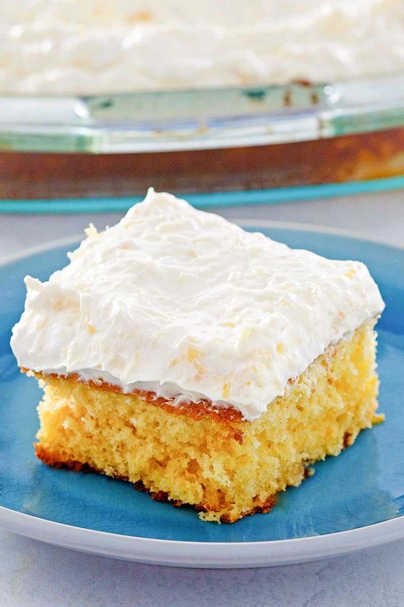 mandarin orange cake slice on a plate in front of the cake.