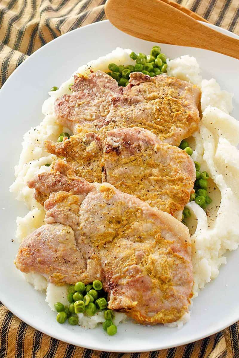 mustard pork chops over peas and mashed potatoes.