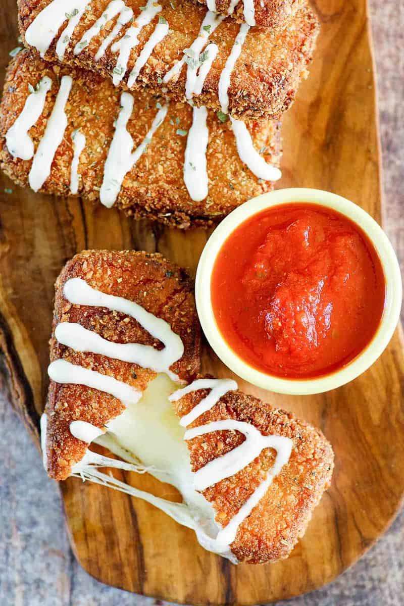 overhead view of homemade Olive Garden fried mozzarella sticks and marinara sauce on a board.