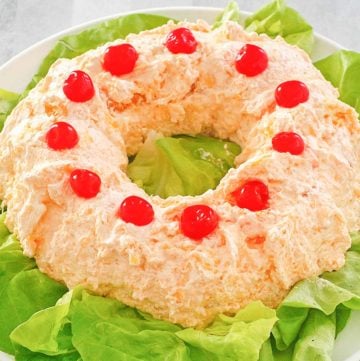 orange fluff jello salad on top of lettuce on a platter.