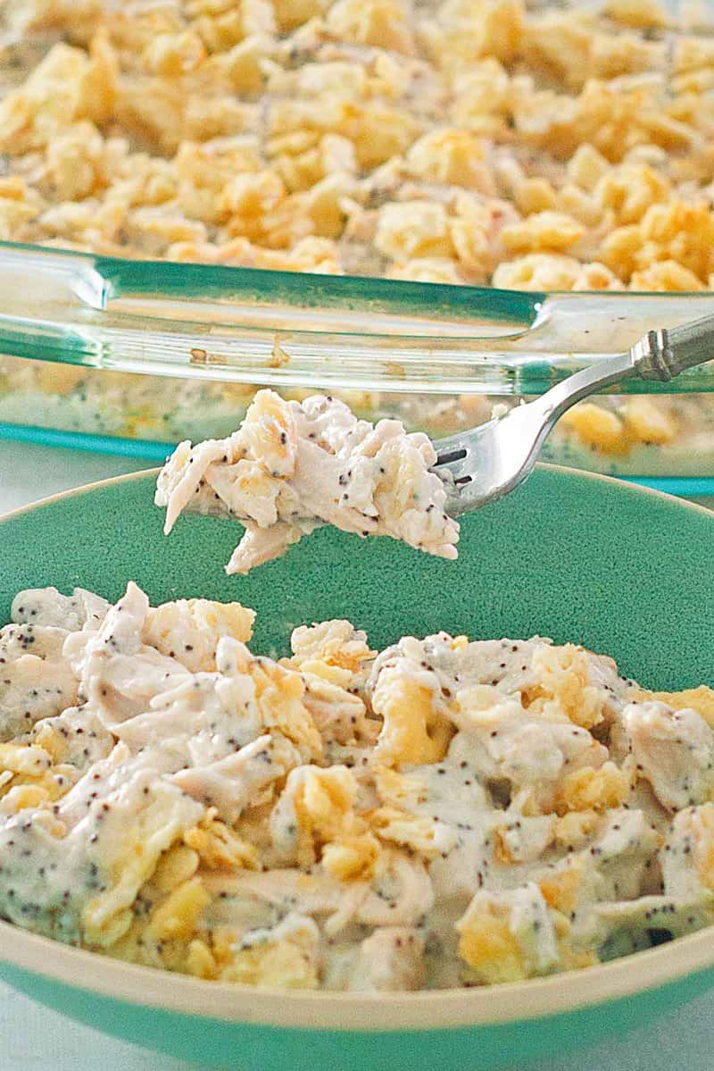 poppy seed chicken casserole on a fork over a bowl of it.