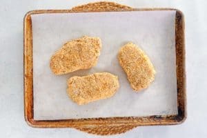 breaded pork loin chops on a baking sheet.