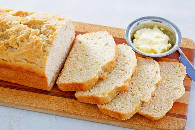 homemade beer bread and a small bowl of butter on a cutting board.