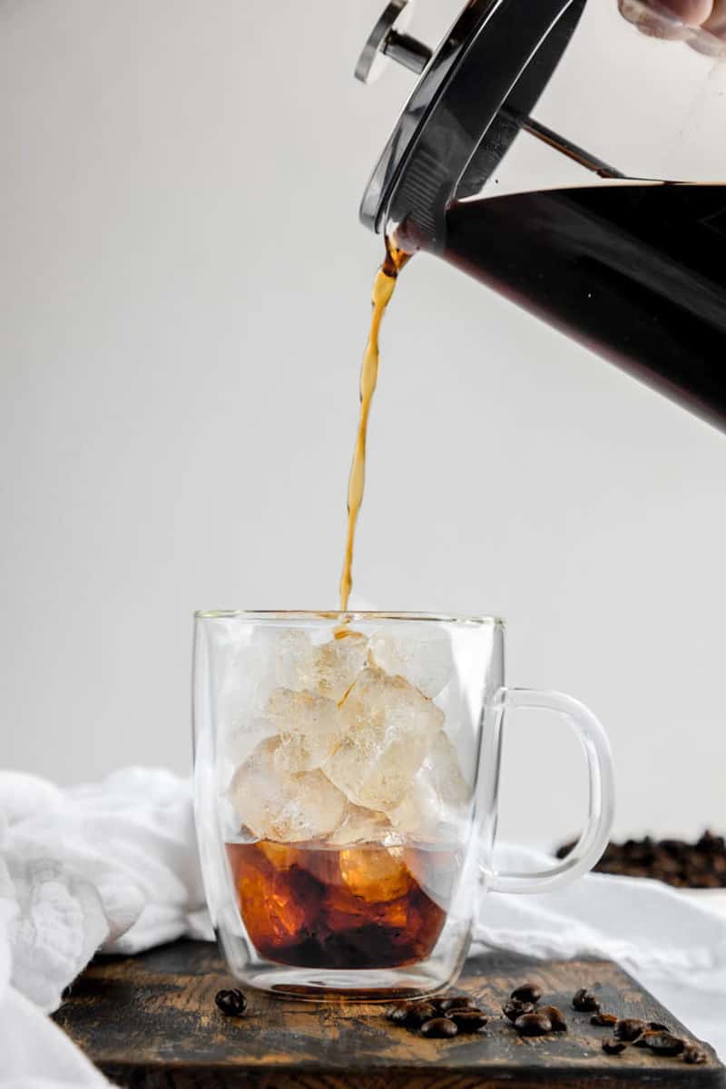 pouring cold brew coffee into a cup with ice.