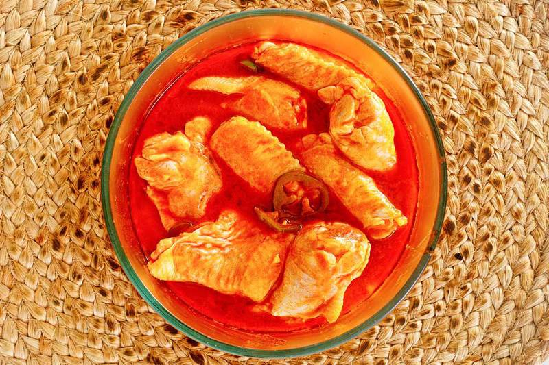 chicken wings marinating in homemade buffalo sauce.