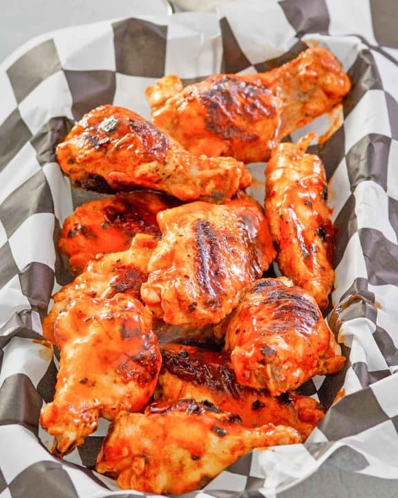 grilled buffalo chicken wings in a parchment paper lined basket.