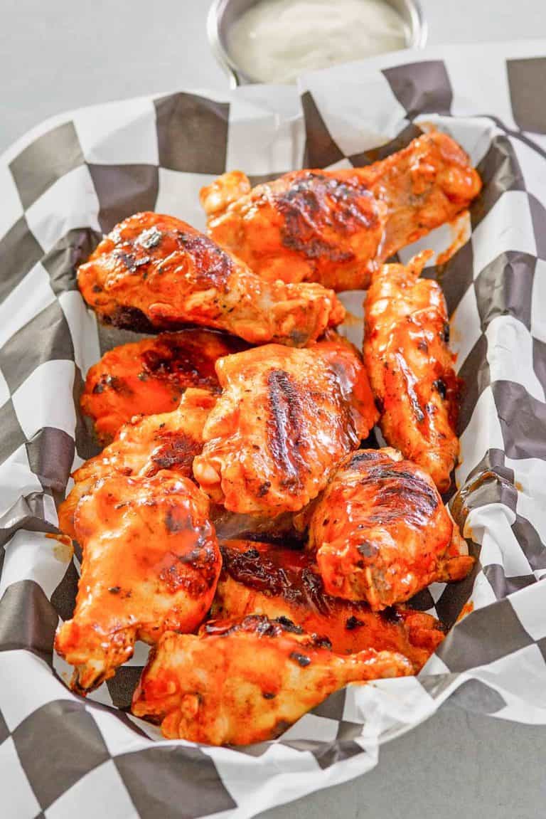 grilled buffalo chicken wings in a parchment paper lined basket.