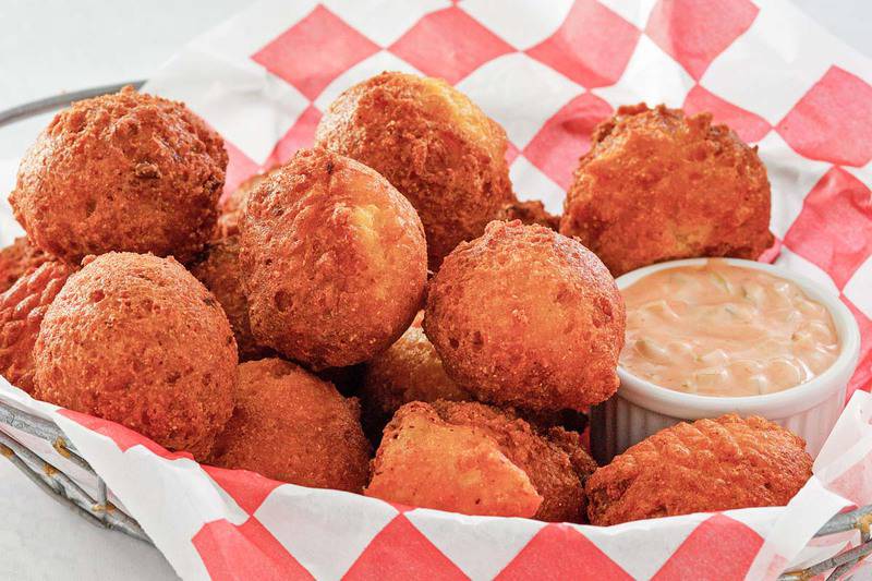 a handbasket  of homemade hush puppies and remoulade sauce.