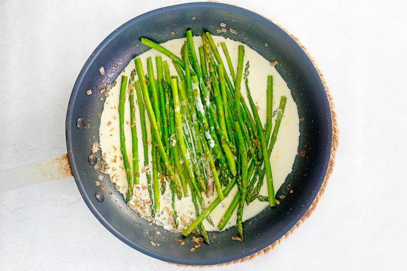 sauteed asparagus and lemon cream sauce in a skillet.