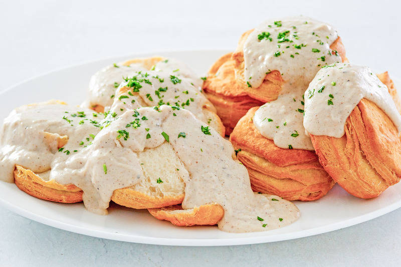 homemade white gravy and biscuits on a platter.