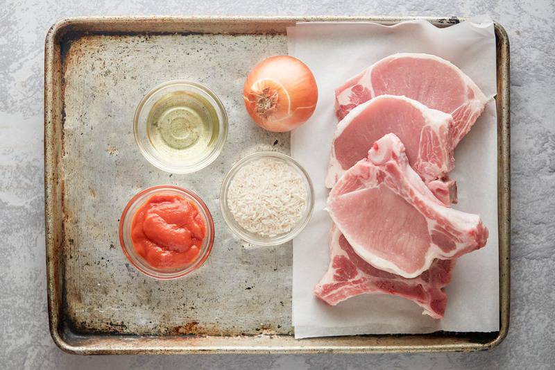 baked pork chops and rice ingredients on a baking sheet.